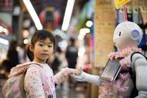 Child holding hands with a robot in Japan. Photo: Andy Kelly, Unsplash